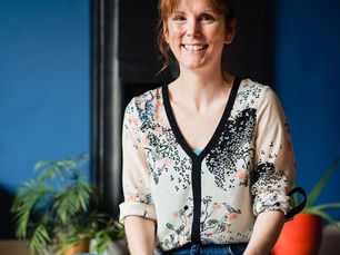 Fiona sits cross legged with a cup of tea
