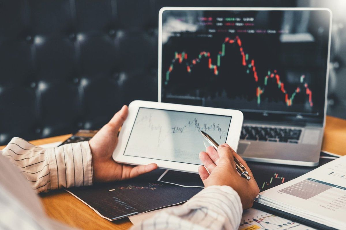 A trader reviewing price charts on a laptop and tablet
