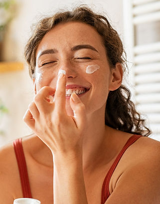 woman applying skincare and smiling