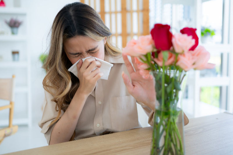 woman sneezing in front of flowers