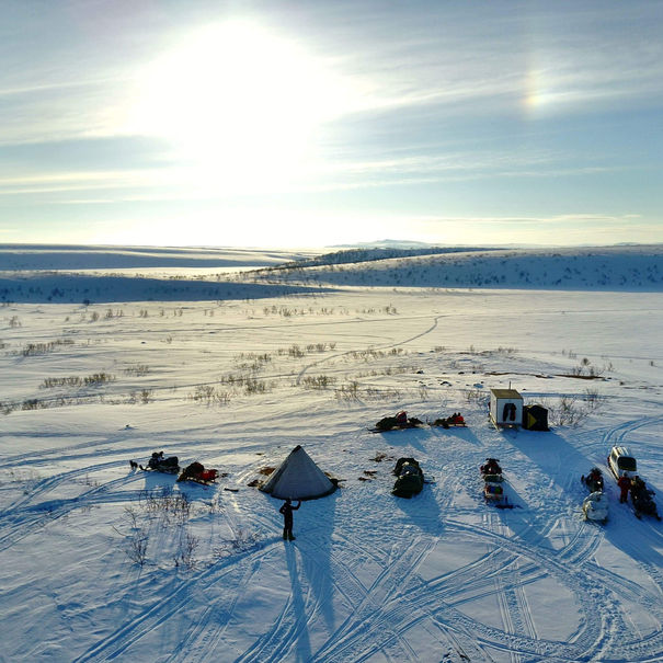 Sámi reindeer herders traveling across frozen Arctic landscape