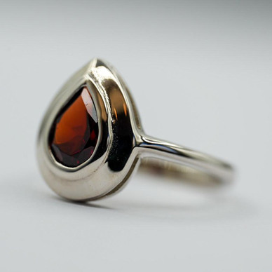 Bague en rhodium avec une pierre facettée en forme de poire de grenat