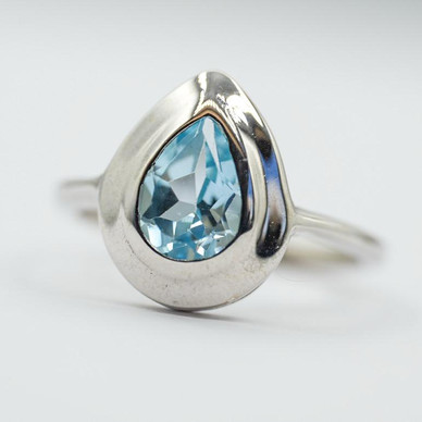 Bague en rhodium avec une pierre facettée en forme de poire de topaze bleue