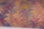 Close up on a marbled paper of a palm pattern with burgundy, navy blue, yellow and pink.