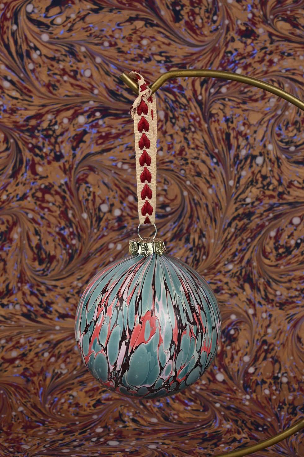 Thumbnail: Close up on a marbled bauble with embroidered ribbon.