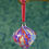 Thumbnail: Close up on a marbled ceramic bauble hanging down, in tones of red, purple and white with velvet ribbon.