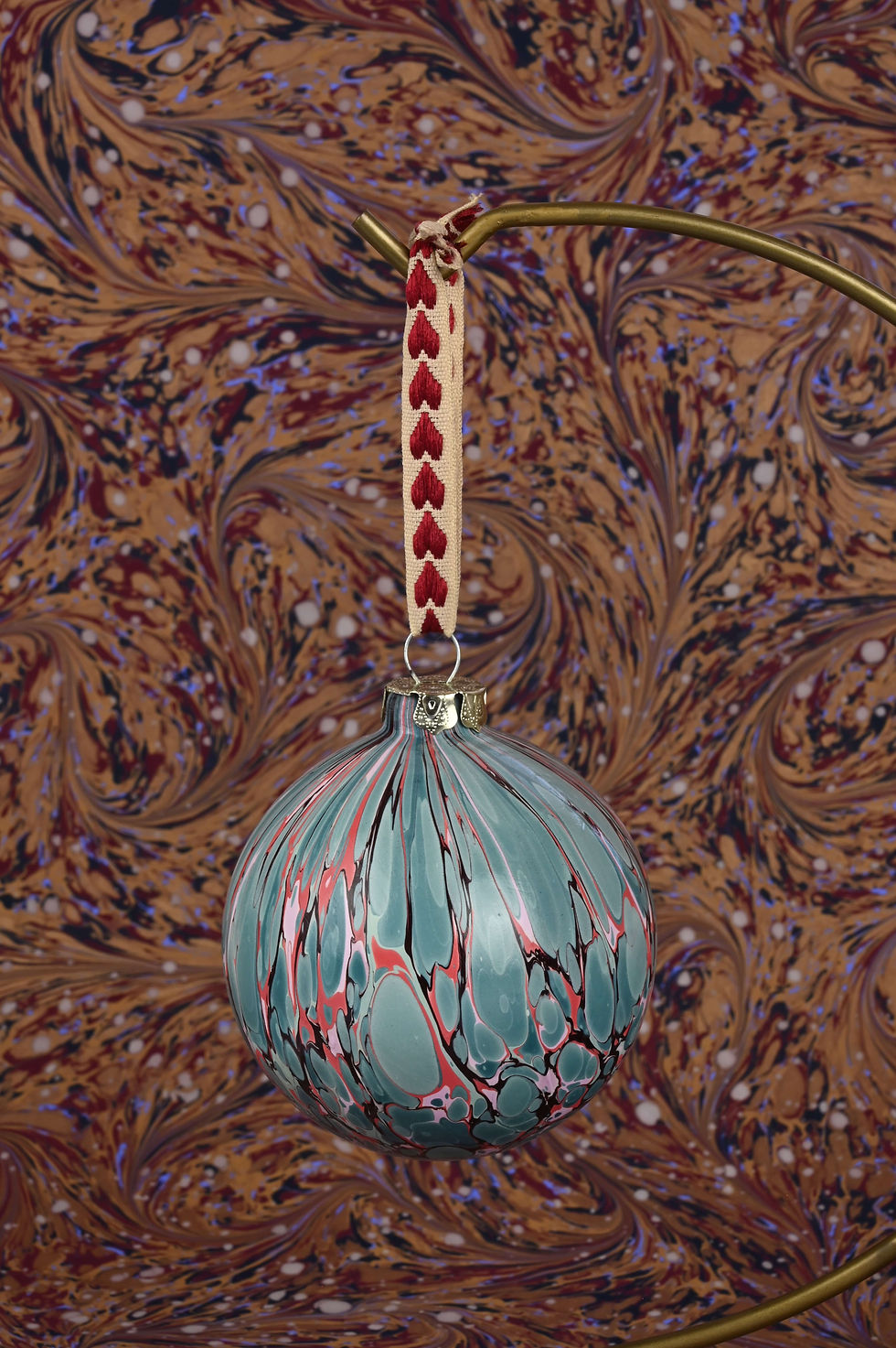 Thumbnail: Close up on a marbled bauble with embroidered ribbon.
