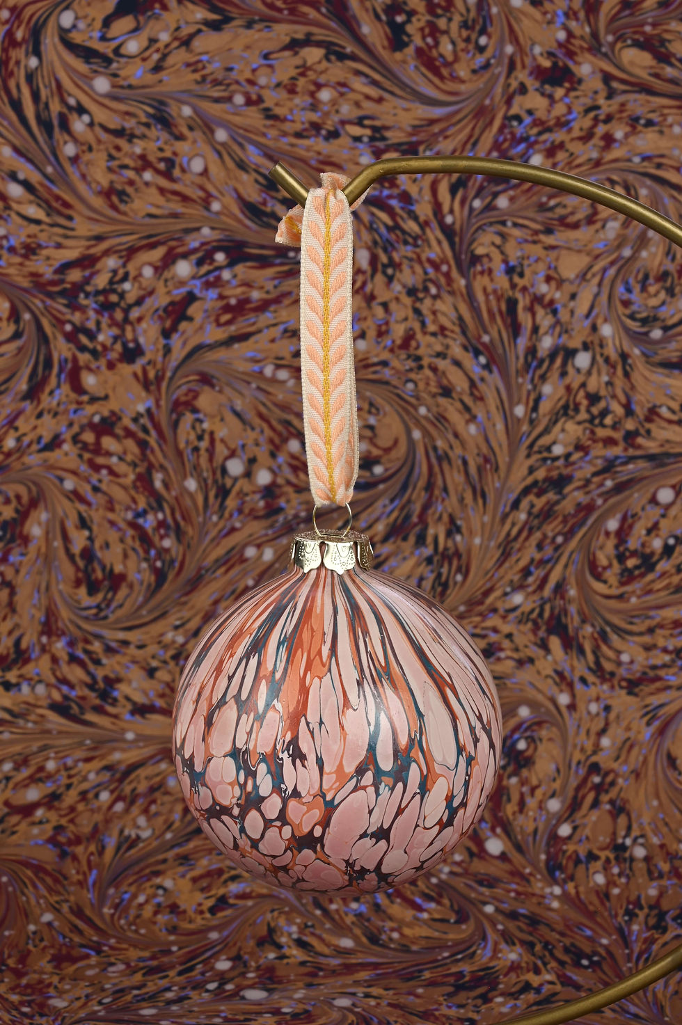 Thumbnail: Close up on a marbled bauble with embroidered ribbon.