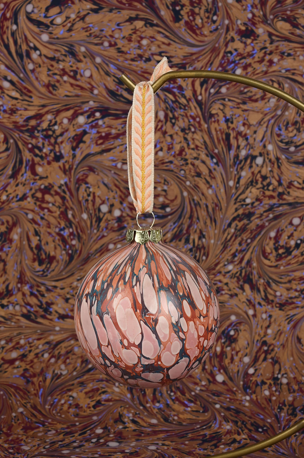 Thumbnail: Close up on a marbled bauble with embroidered ribbon.