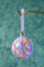 Thumbnail: Close up on a marbled ceramic bauble hanging down in light blue, purple and red, with velvet ribbon.