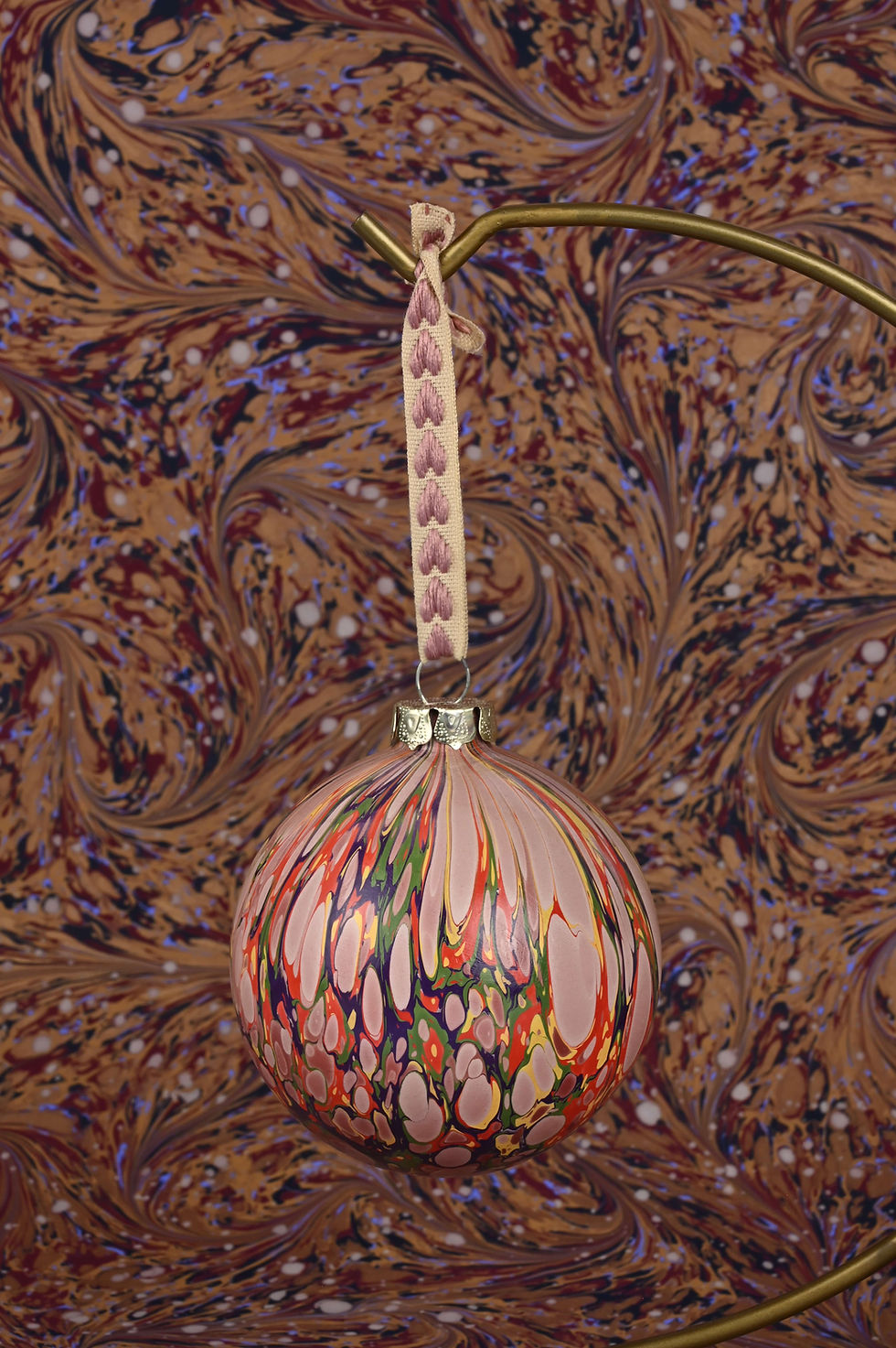 Thumbnail: Close up on a marbled bauble with embroidered ribbon.