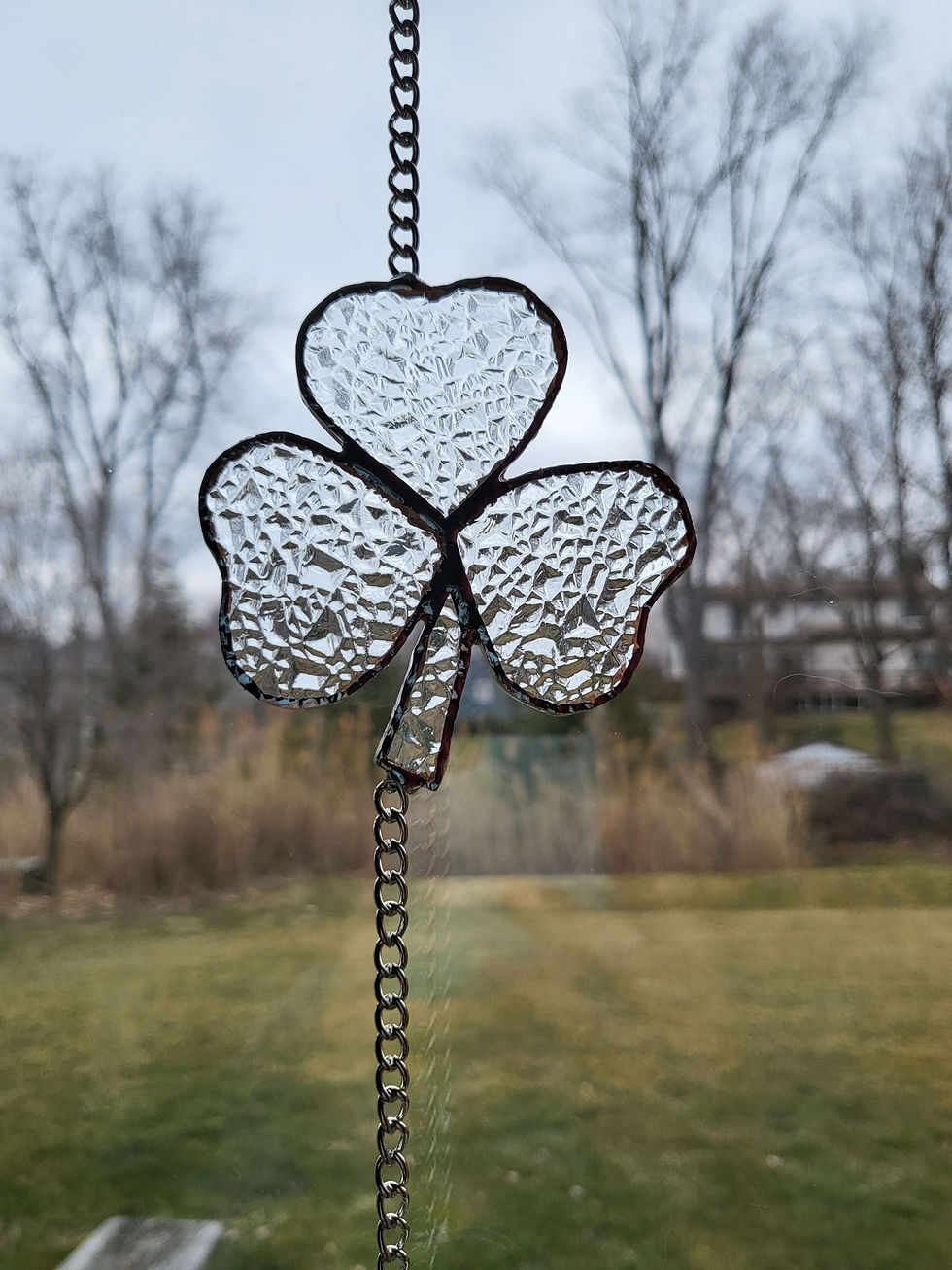 Thumbnail: St Patrick's Day 4 Shamrock String Suncatcher hanging in front of trees and grass