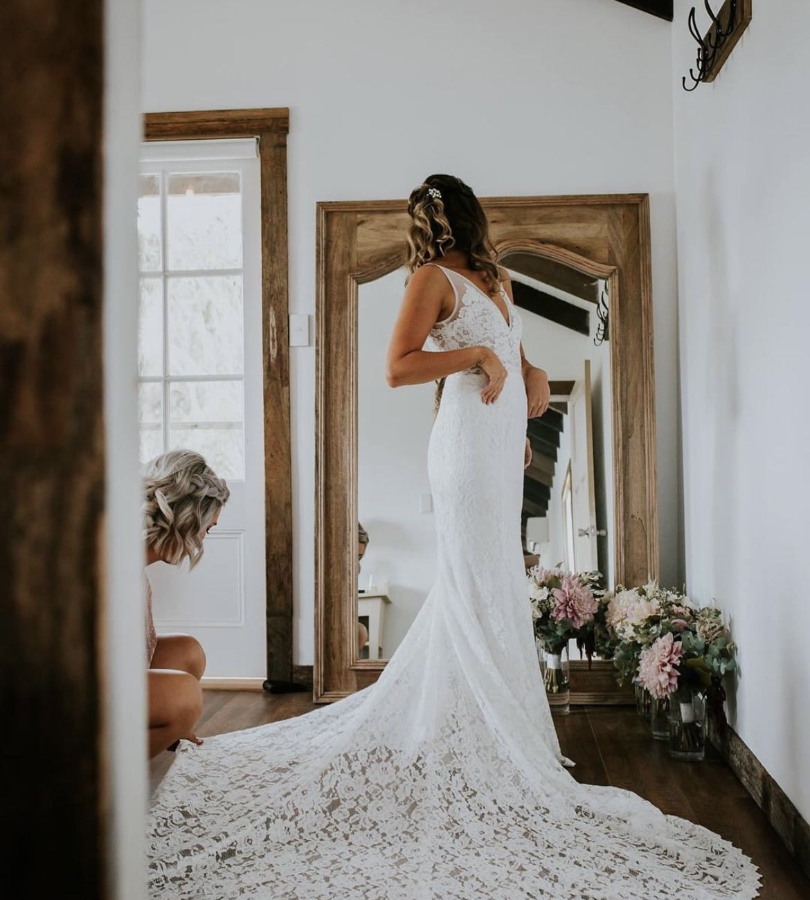 Bride checking her lace gown and long train in the full length mirror in the Loft