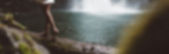 Lady walking on a rock near a waterfall