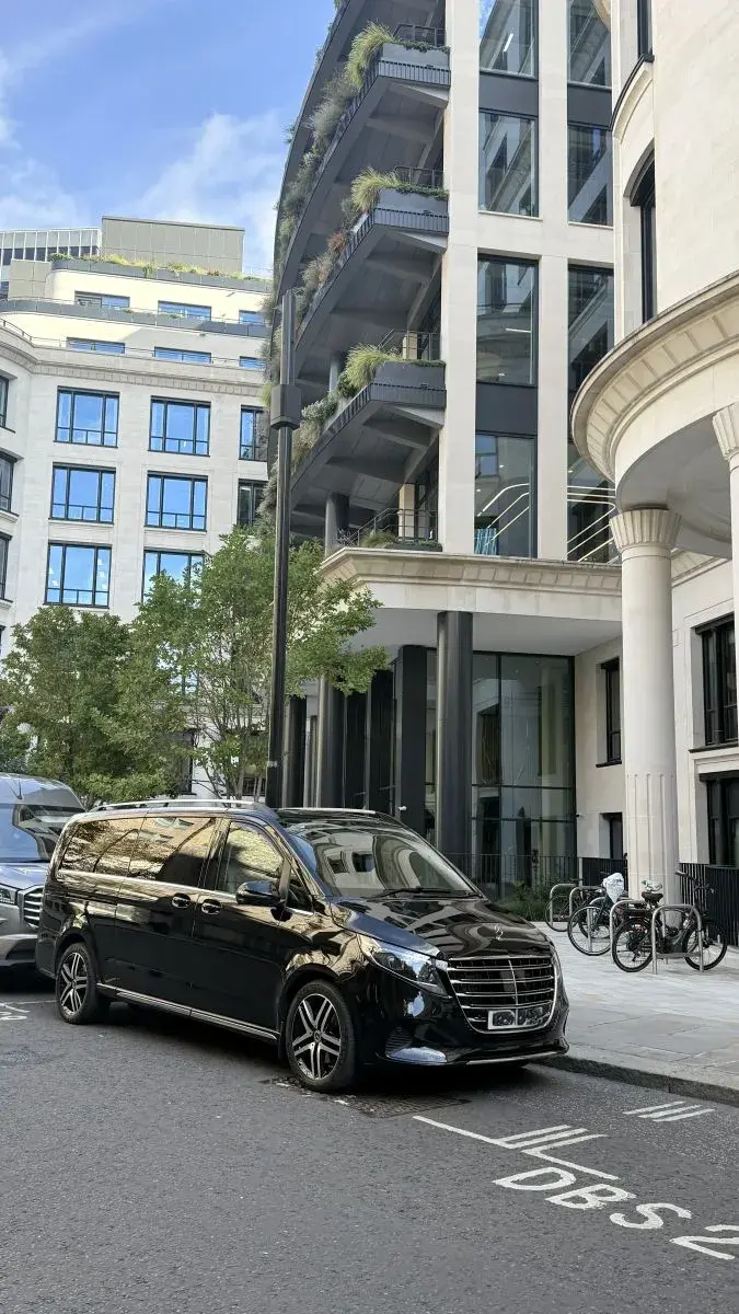 Black Mercedes van parked on a city street beside modern office buildings