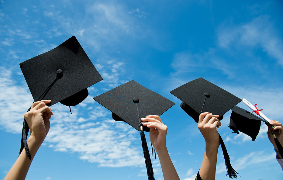 Many hand holding graduation hats on bac