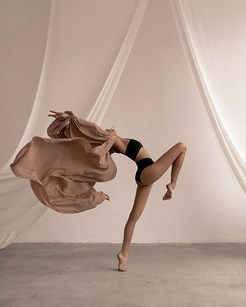 woman dancing in black underwear woth beige sheets around her
