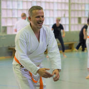 Mann lacht fröhlich im weißen Karate-Gi mit orangefarbenem Gürtel.