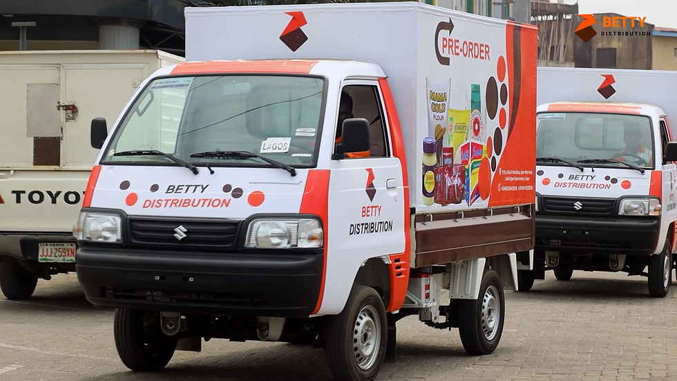Two white and red delivery trucks labeled "Betty Distribution" with grocery images and "Pre-order" sign against an urban street backdrop.