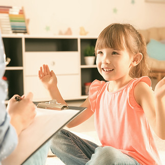 A child smiling at a person holding a clipboard