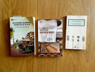 Tre libri su un tavolo in legno: Esercizi di stile di Raymond Queneau, Specie di spazi di Georges Perec e Le città invisibili di Italo Calvino
