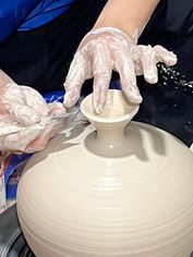 Hands shaping clay vase on pottery wheel