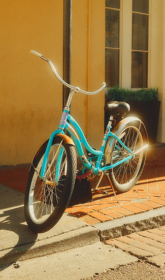 Blue and chrome cruiser bicycle in front of a yellow wall. 