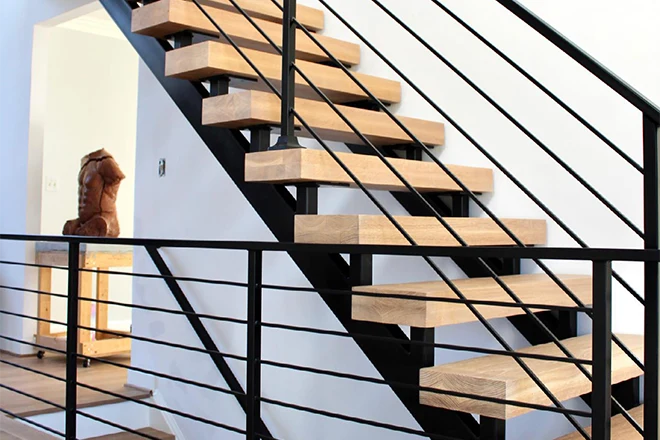 Light brown wood stairs with black metal rail and cable balusters
