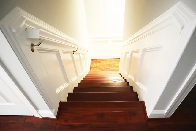 Descending wood staircase with white walls
