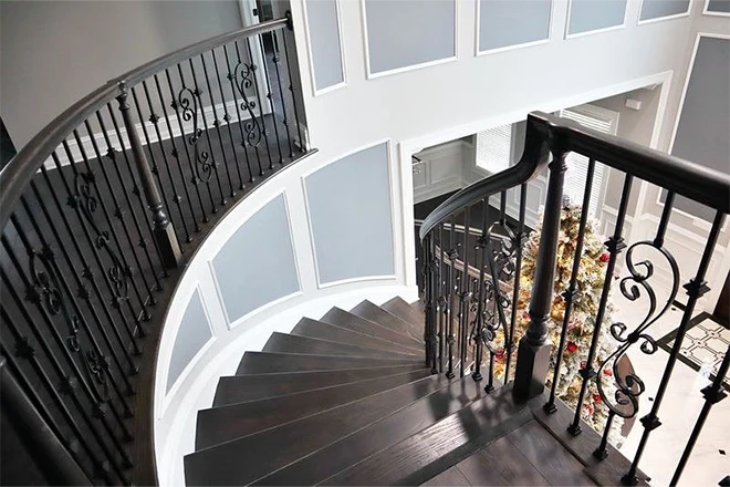 Curved stairs with dark wood stain and ornate railing and balusters