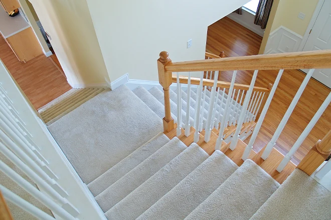 Stairs with gray carpet and light wood handrail