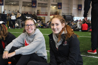 two women in hoodies sit and smile at camera