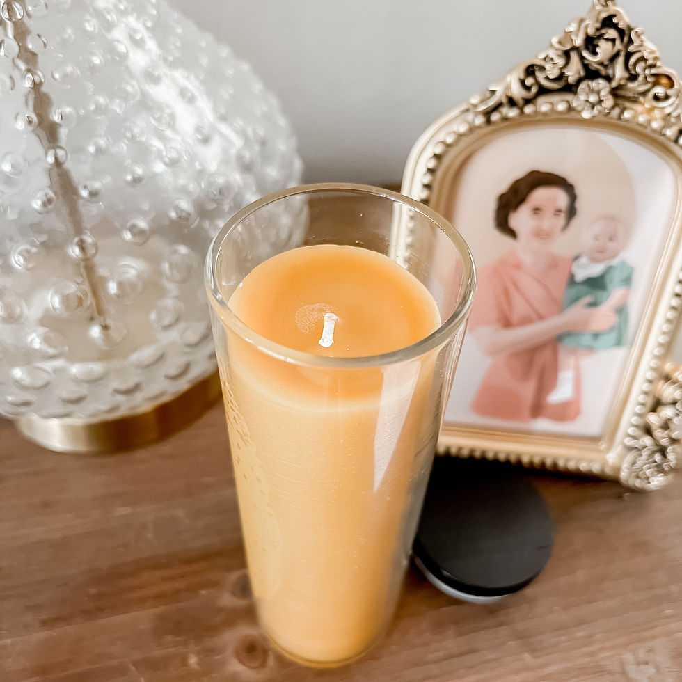 Beeswax pillar candle on a side table next to a framed image of St. Gianna Molla.