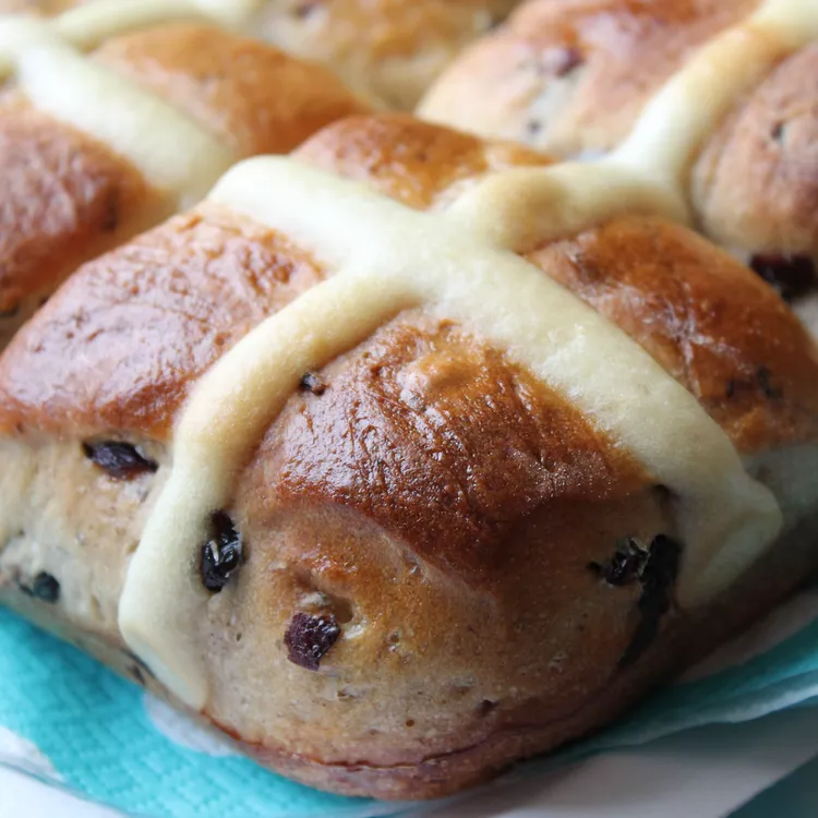 Hot cross buns sitting on a blue lined plate. His Girl Sunday recipe for Holy Week and Good Friday during Catholic Lent.