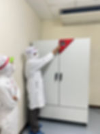 Technician in white uniform inspecting lab equipment.