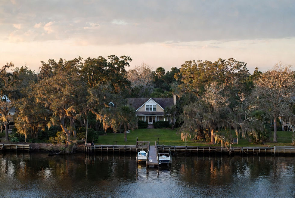 Charming waterfront home with private wooden dock on the St. Johns River in Putnam County Florida at golden hour, framed by large live oak trees with Spanish moss
