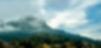 Foggy mountain peak above green forest