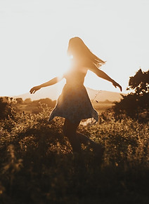 Frau tanzt auf Feld im Sonnenuntergang