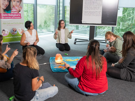 Mamas mit Babys sitzen im Kreis und singen ein Lied begleitet mit Gebärden.