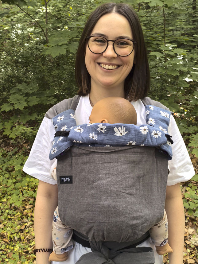 Trageberaterin trägt eine Tragepuppe in einer Babytrage.