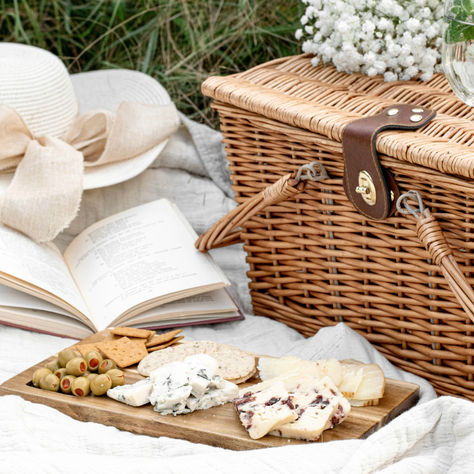 Picnic all’aperto con cappello di paglia, libro e cibo, simbolo di relax e digital detox.