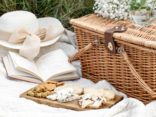 Picnic all’aperto con cappello di paglia, libro e cibo, simbolo di relax e digital detox.