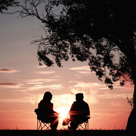 Due persone si ascoltano in silenzio durante il tramonto, simbolo di presenza e connessione autentica.