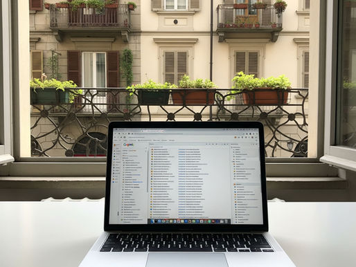 Laptop MacBook su scrivania bianca davanti a una finestra di Torino con Gmail in italiano pieno di email non lette