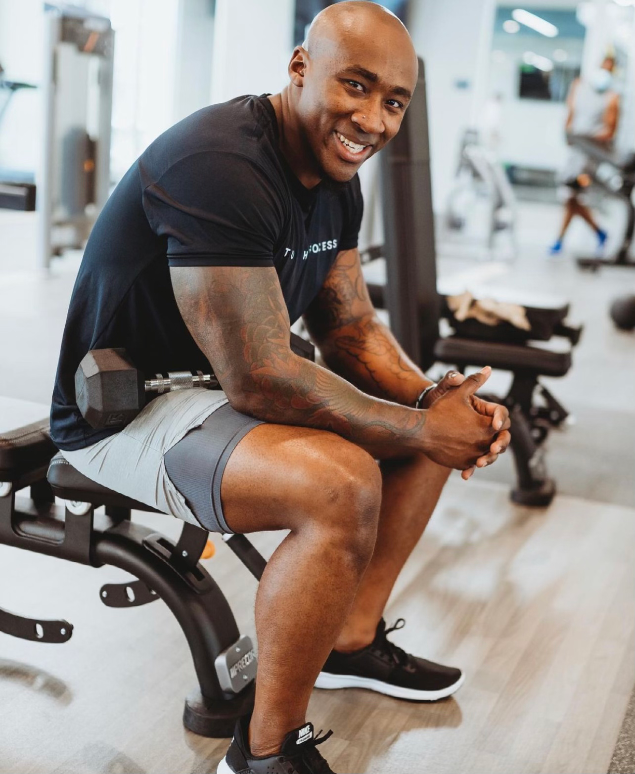 A member seated on a bench mid-set inside JTM Fitness Gym