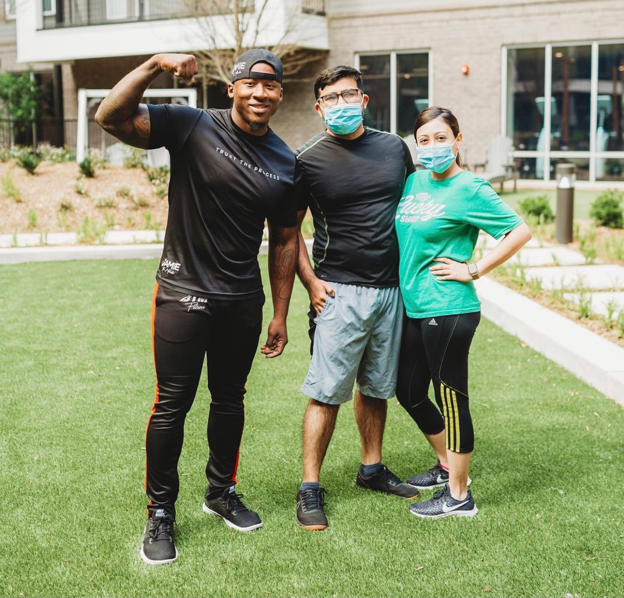 A JTM coach standing with two clients on the lawn after an outdoor session