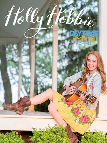 A poster for the daytime Emmy nominated Holly Hobbie. The poster features a teenage girl sitting on the porch of a house with a guitar in her hands.