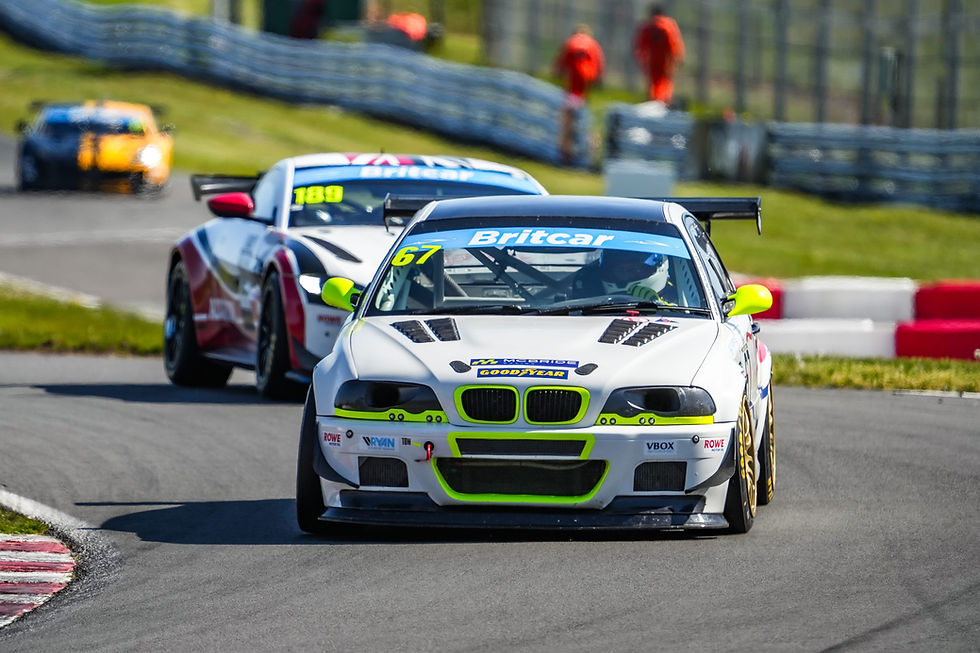 Julian McBride leading an Aston Martin around Knickerbrook at Oulton Park.