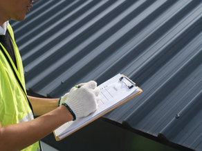 Tucson roofing contractor inspecting a metal roof with a clipboard checklist, performing a professional roof maintenance evaluation in Southern Arizona