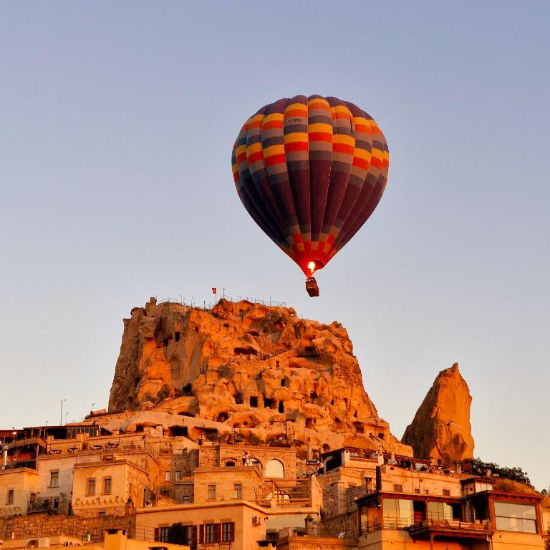 Colorful hot air balloon flying above Uchisar Castle Cappadocia at sunrise_edited